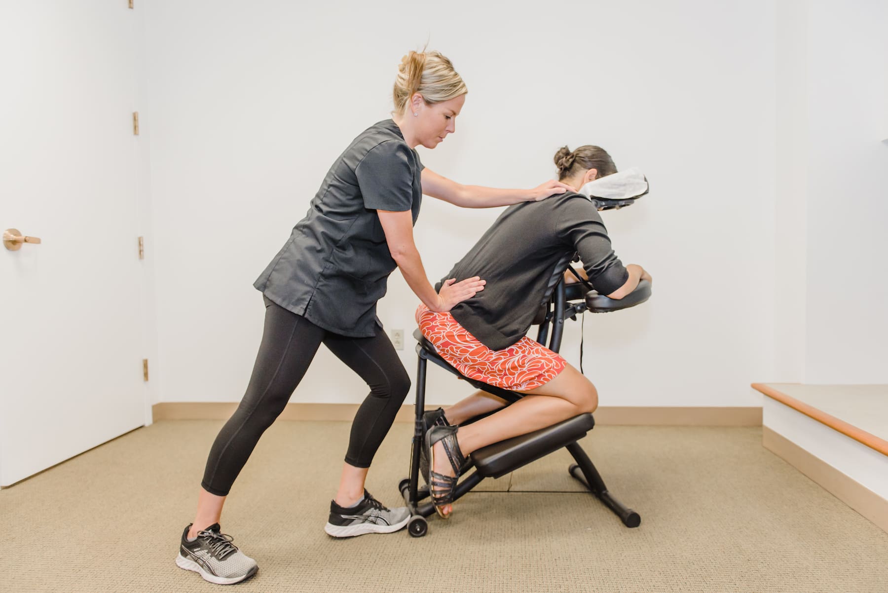 Corporate Chair Massages Owner Jeannette Sweeney providing a chair massage to a female customer.