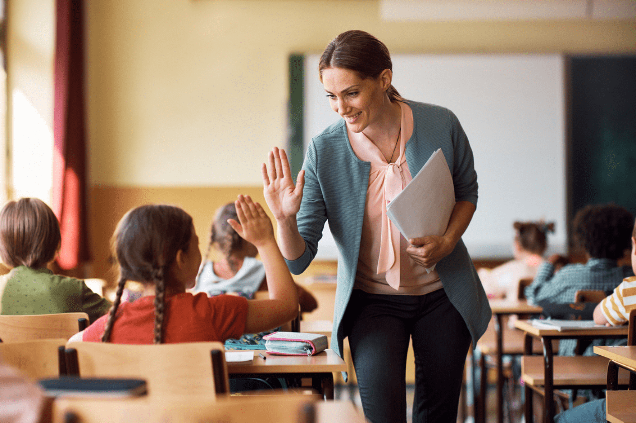 Female school teacher high-fives a female student with braids