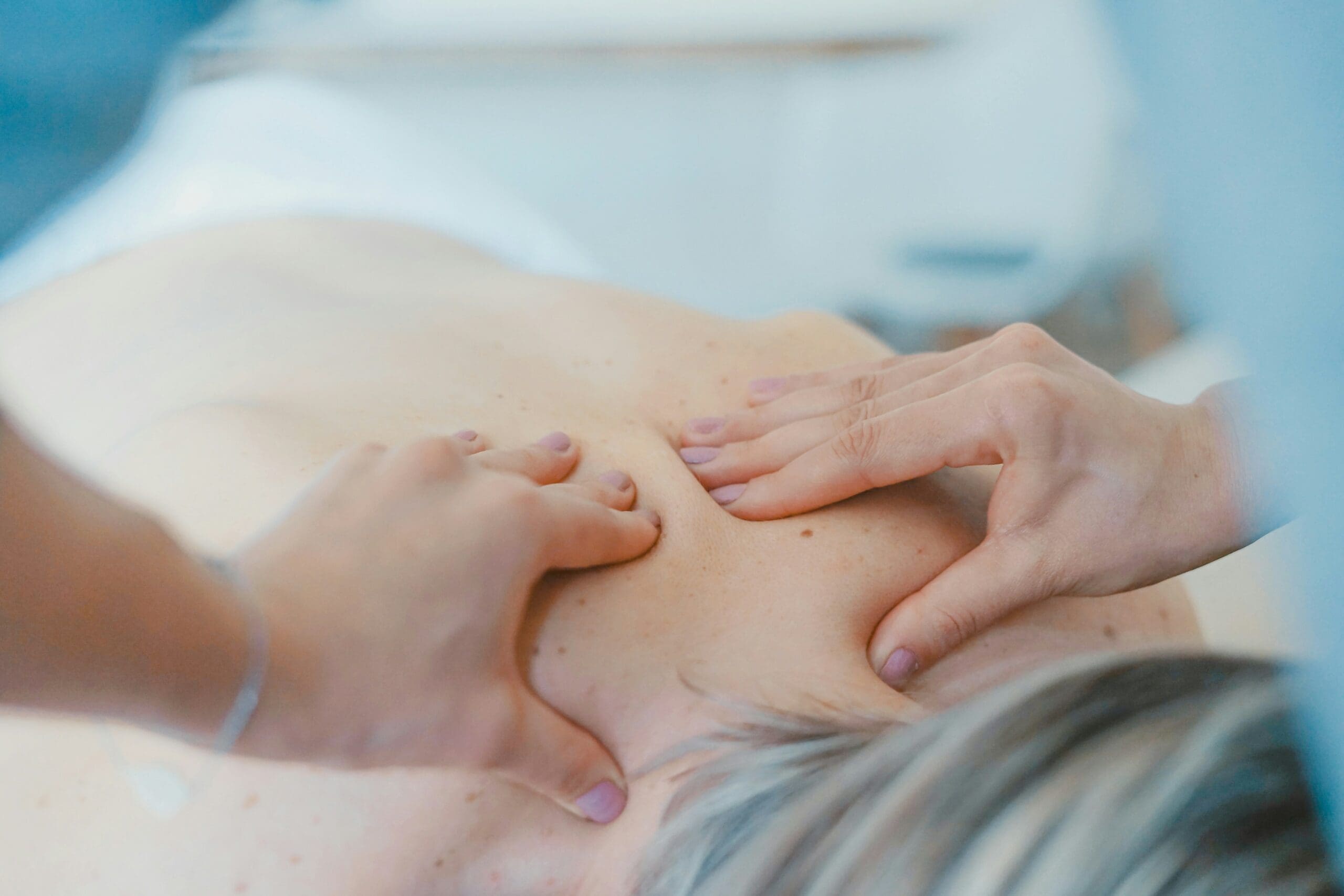 Posterior photo of unclothed back with two hands squeezing the upper trapezius