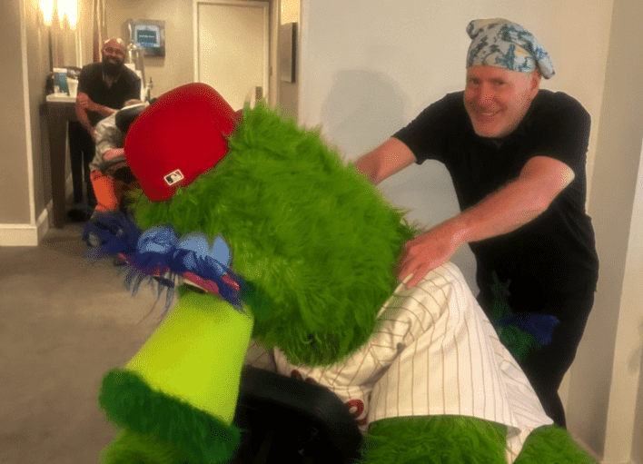 Massage therapist gives chair massage to Philadelphia Phillies Phanatic team mascot